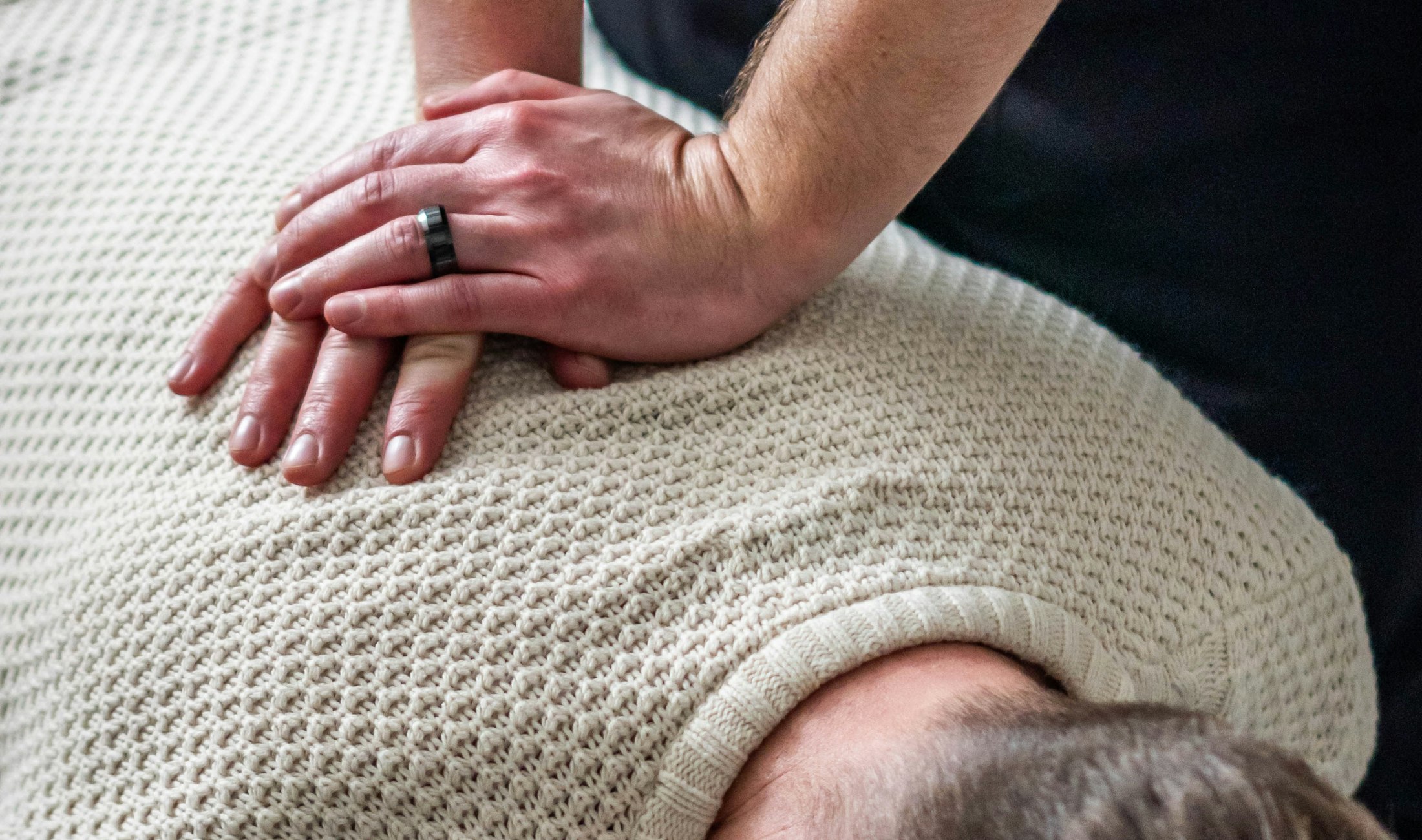 Practitioner's hands providing hands-on care to a patient's upper back